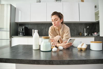 Portrait of young woman having food at home