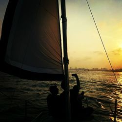 Ship sailing in sea at sunset