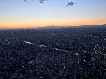 Aerial view of illuminated cityscape against sky during sunset