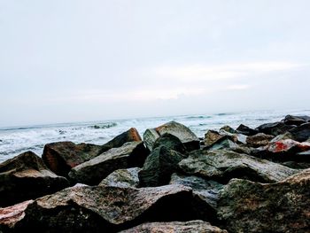 Close-up of rocks by sea against sky