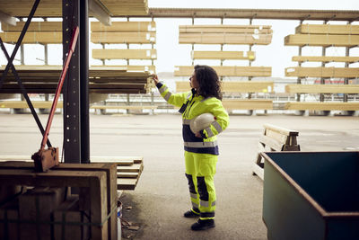 Side view of female worker examining planks stacked at lumber industry