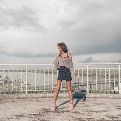 Full length of woman standing by railing against sky