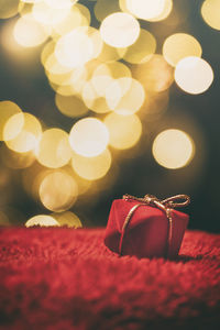 Close-up of christmas present against illuminated defocused lights at night