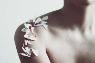 Close-up of woman with flowers against white background