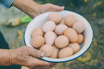 Cropped hands of senior woman holding eggs in bowl