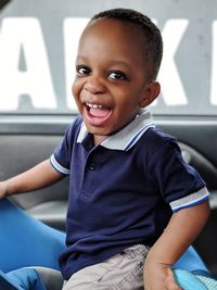 Portrait of cheerful baby boy sitting in car