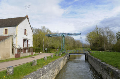 Bridge over canal amidst buildings against sky