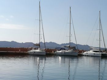 Sailboats moored in harbor against sky