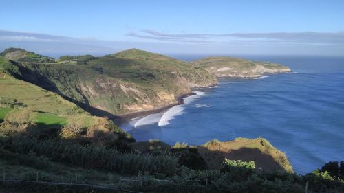 Scenic view of sea and mountains against blue sky
