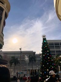 People on christmas tree in city against sky