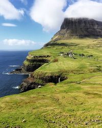 Scenic view of landscape by sea against sky