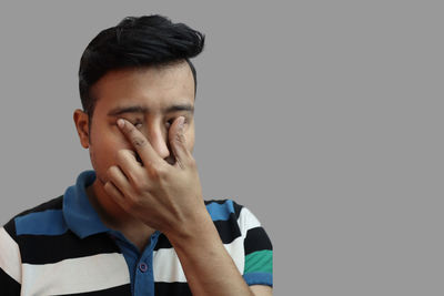 Close-up portrait of man covering face against black background