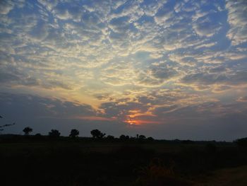 Scenic view of silhouette field against sky at sunset