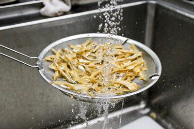 High angle view of anchovies getting washed in colander