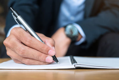 Midsection of man holding paper with text on table