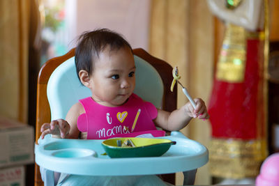 Portrait of cute girl sitting on table at home