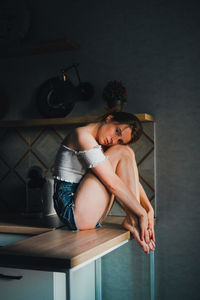 Young woman sitting on table at home