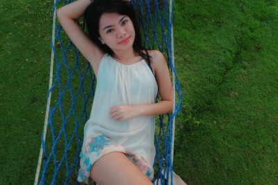 Portrait of beautiful woman relaxing on hammock at field