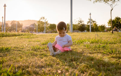 Cute girl sitting on field at park
