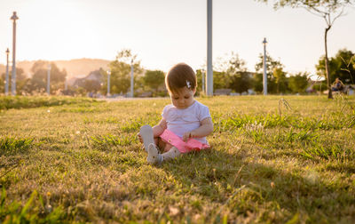 Full length of cute girl sitting on field
