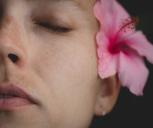 Close-up portrait of woman with pink flower