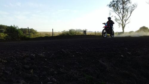 Man riding motorcycle on field against sky