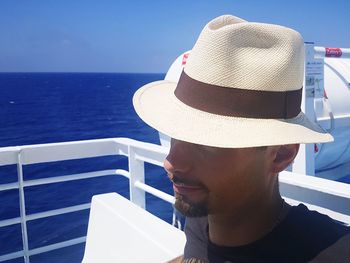 Close-up of mid adult man wearing hat in boat on sea against sky