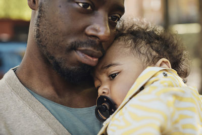 Father carrying toddler boy with pacifier in mouth