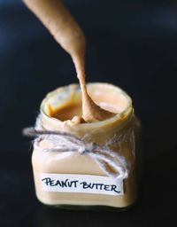 Close-up of peanut butter in jar against black background