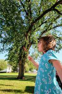 Side view of girl standing against trees