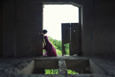 Side view of woman standing against building