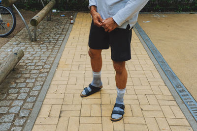 Low section of man standing on cobblestone