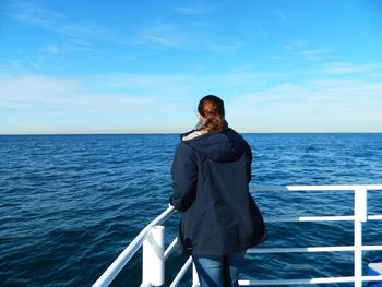 Rear view of person looking over sea against clear sky