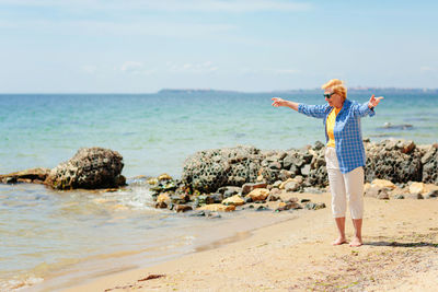 Elderly woman walking on the beach near the sea