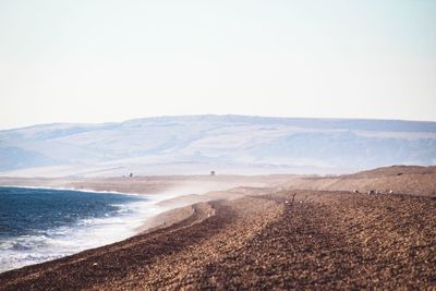 Scenic view of land and sea against clear sky