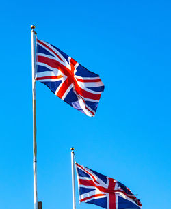 Low angle view of flag flags against clear blue sky
