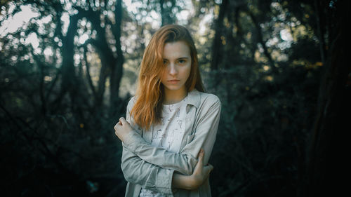 Young woman standing against trees