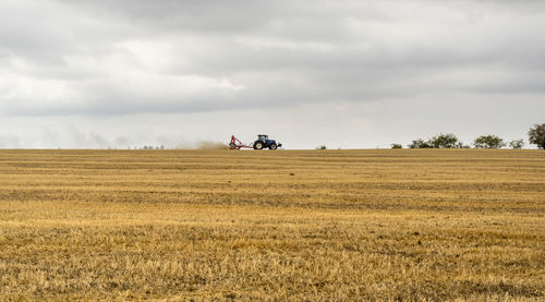 Stormy farmland scenery showing a tractor on a stubble field in hohenlohe