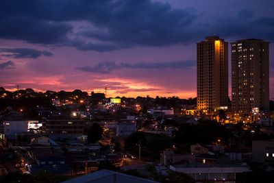 Illuminated buildings in city against sky at sunset