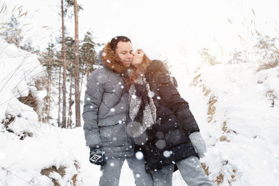 Woman kissing man during snowfall