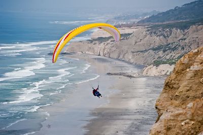 High angle view of person paragliding over sea against mountain
