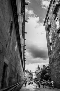 People on street amidst buildings in city against sky