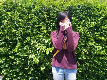 Young woman standing against tree