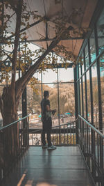 Man standing by railing against trees