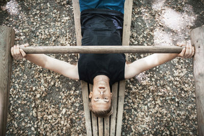 High angle view of man lifting wooden weight at outdoor gym