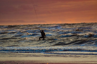 Silhouette man surfing in sea against sky during sunset