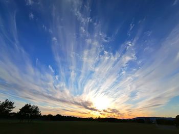 Scenic view of silhouette field against sky at sunset