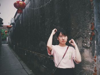 Young woman standing by wall