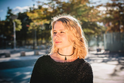 Close-up of young woman standing against trees