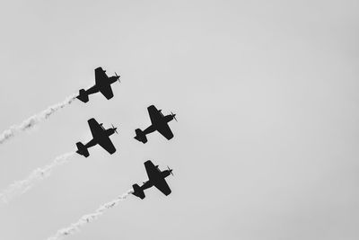 Four aerobatic planes flying in formation in clear sky.